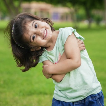 Happy cute little indian girl child standing having fun at summer park or garden.