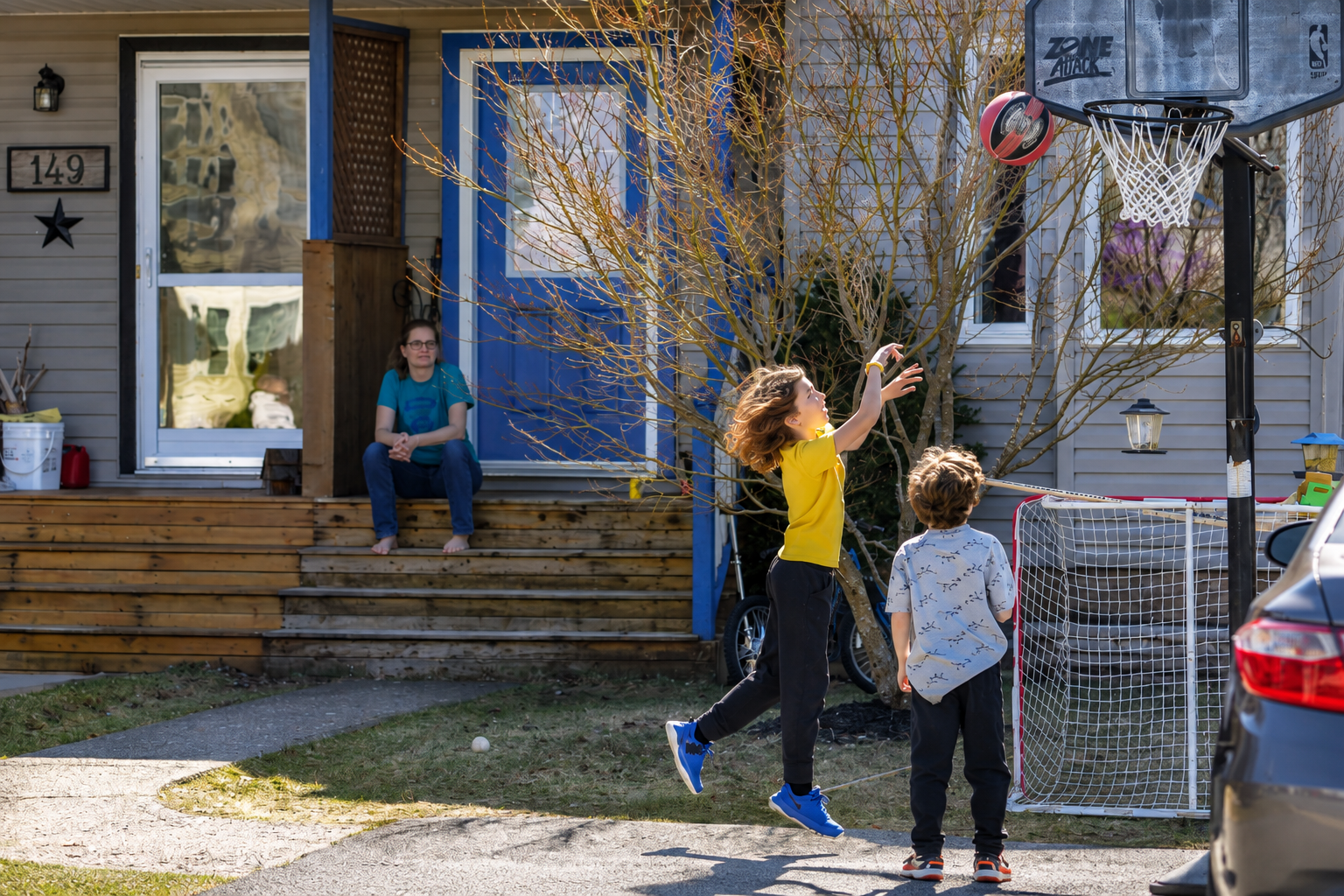 Children playing basketball outside a home